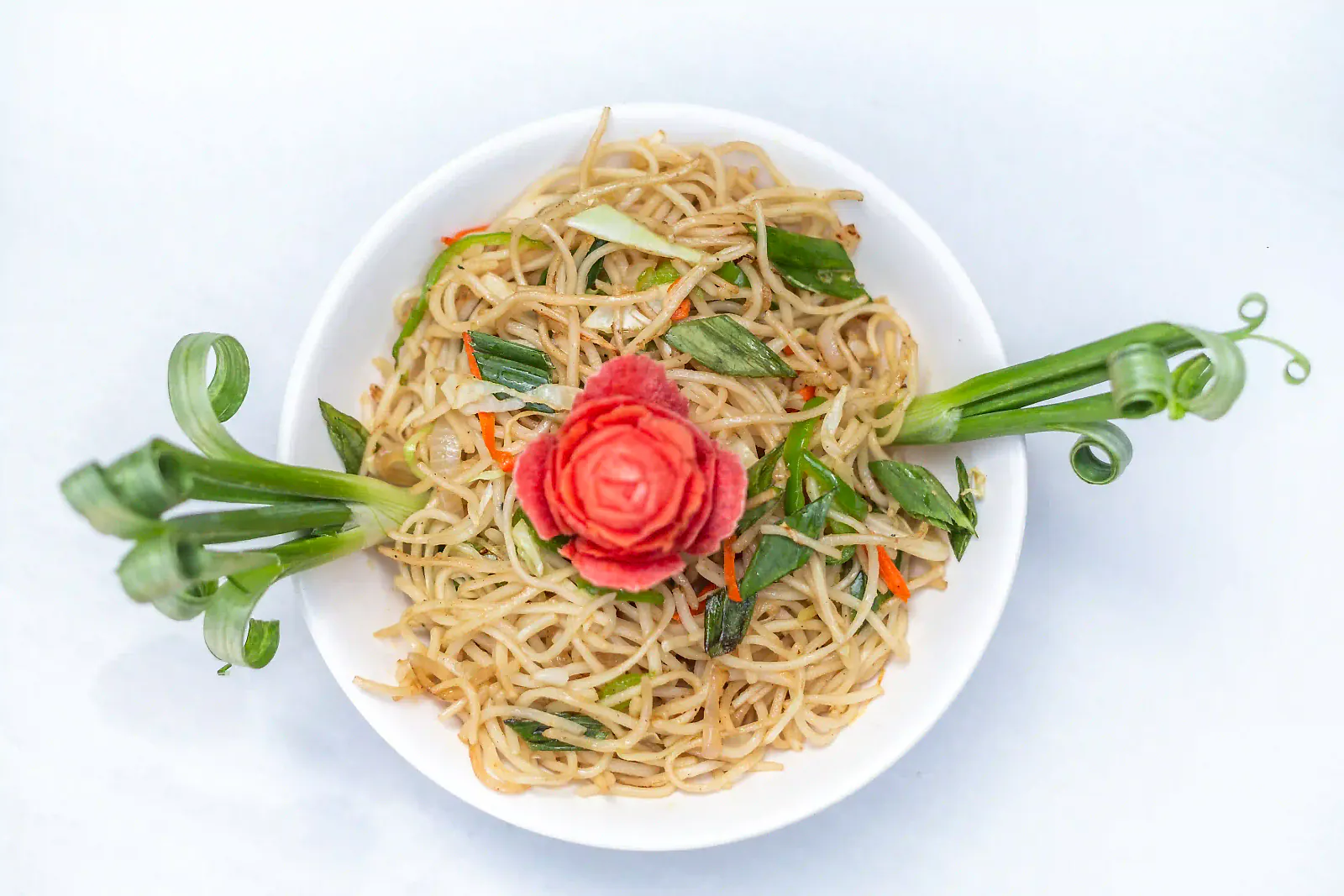 Stir-fried noodles with a carved tomato rose