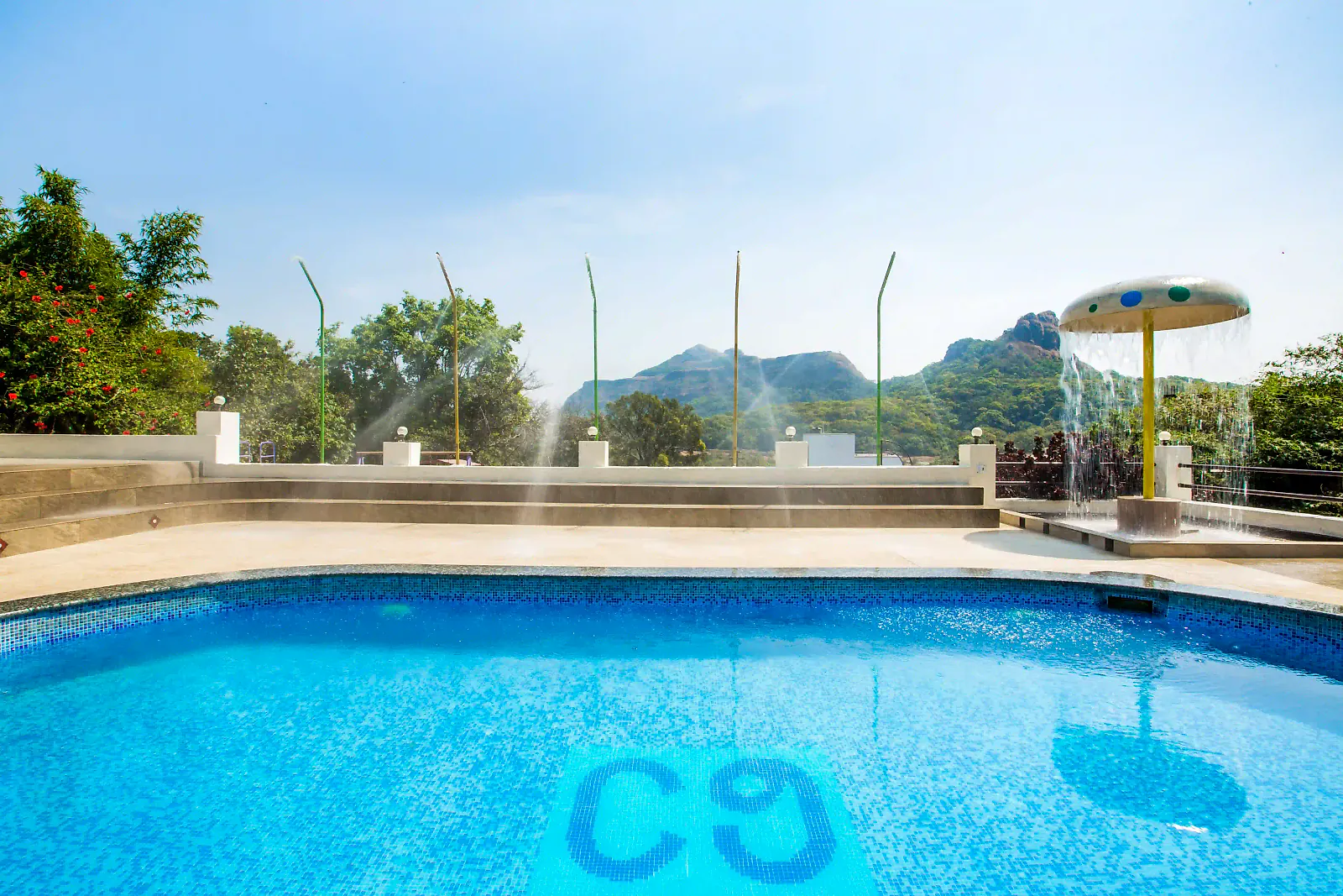 The swimming pool at Cloud 9 Hills Resort with the Sahyadri hills behind