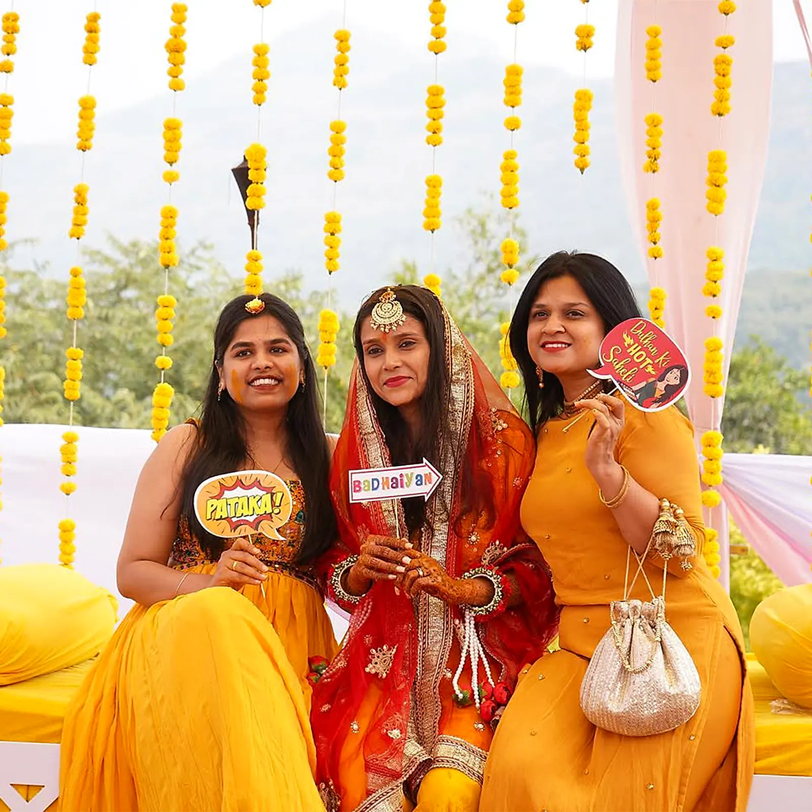 The bride laughing with friends at her haldi, dressed in yellow