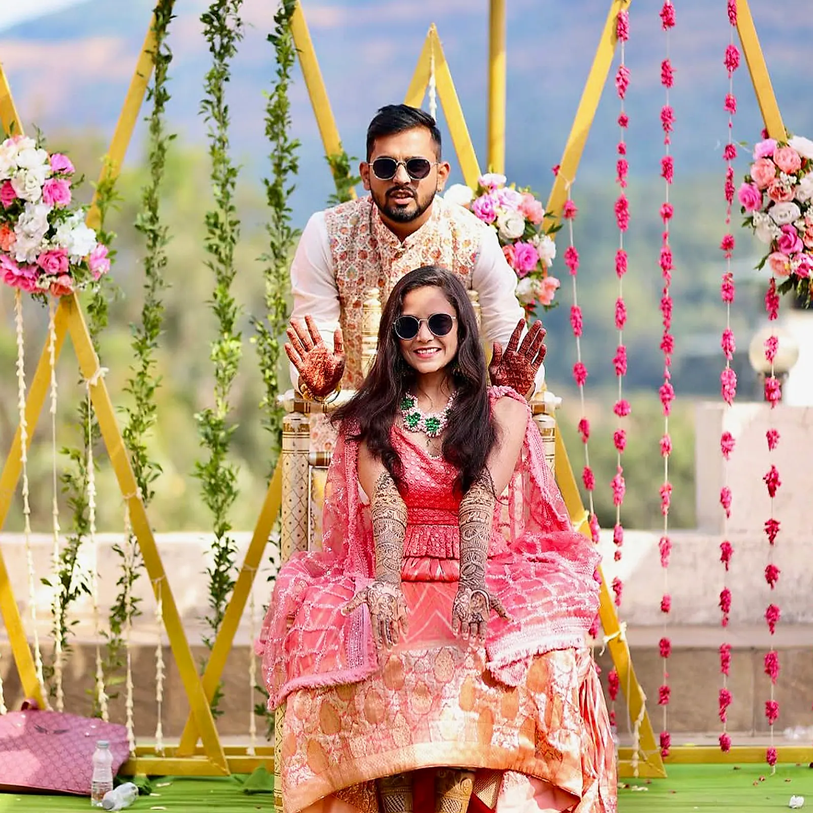 The couple posing on a floral swing at their mehndi