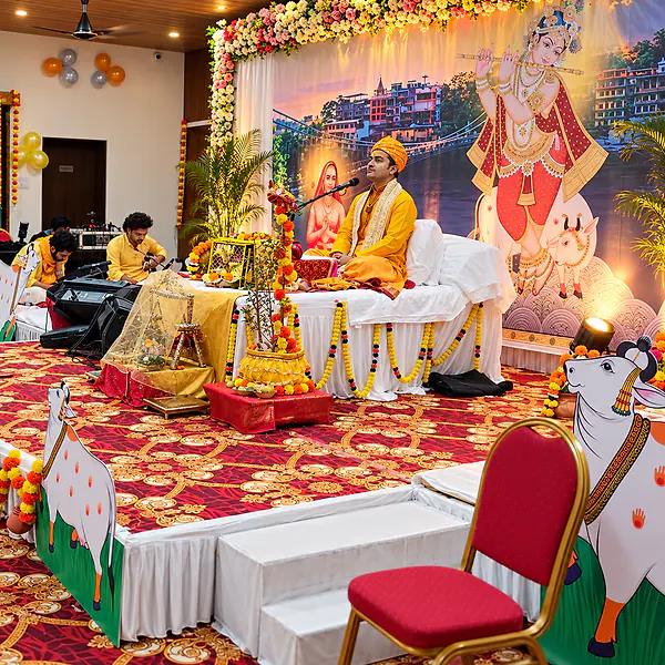 A singer leading devotional bhajans on a flower-decorated stage