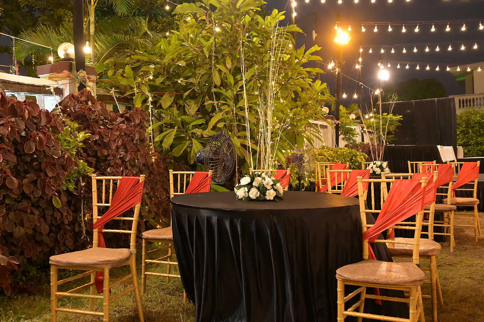 Dressed tables on the lawn under string lights at night